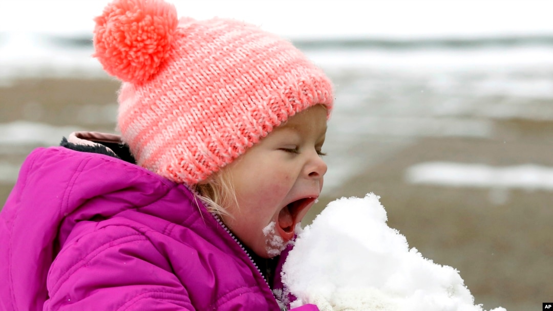 Emmaline Dendinger enjoys a big bite of snow as she plays in her Jackson, Mississippi neighborhood, Dec. 2017. (AP Photo/Rogelio V. Solis)