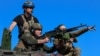 Miembros del servicio de la 37ª Brigada de Infantería de Marina de Ucrania utilizan una ametralladora encima de un vehículo de combate blindado francés AMX-10 RC durante ejercicios militares, en un lugar no revelado en el sur de Ucrania el 3 de abril de 2024.