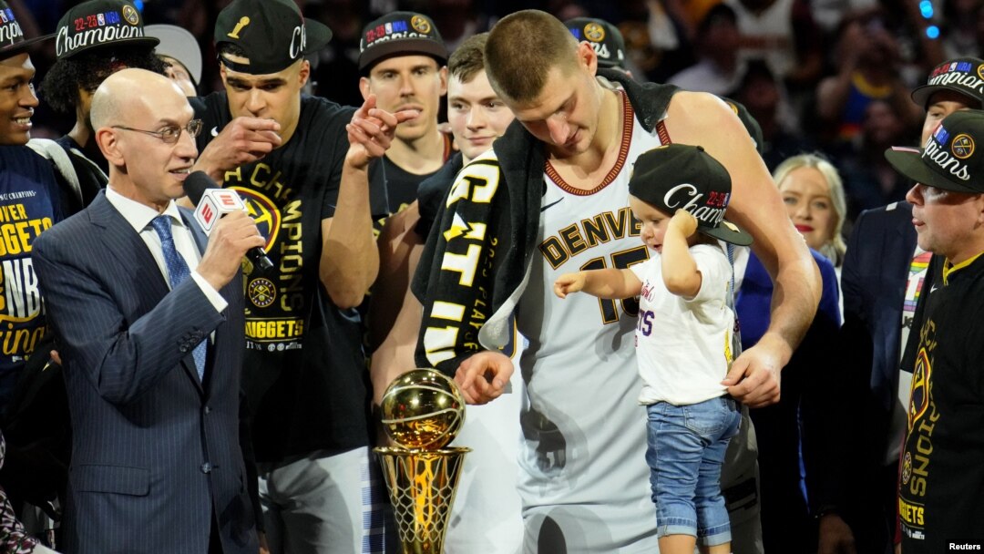Nikola Jokić i njegova ćerka Ognjena pokazuju prstom na trofej "Bil Rasel", koji je Jokić dobio kao MVP finala plej-ofa (Foto: USA TODAY Sports/Kyle Terada)