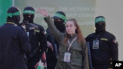 La soldado israelí Agam Berger saluda a la multitud junto a militantes enmascarados de la Jihad Islámica mientras es entregada a la Cruz Roja en el campo de refugiados de Jabalia en la ciudad de Gaza, el 30 de enero de 2025.